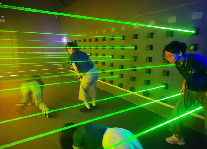 Players navigating an illuminated laser maze challenge